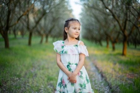 Happy little girl in floral dress spending time at the park