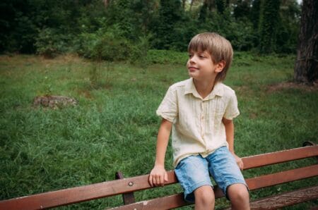 Young blonde boy sitting on the railing at the park