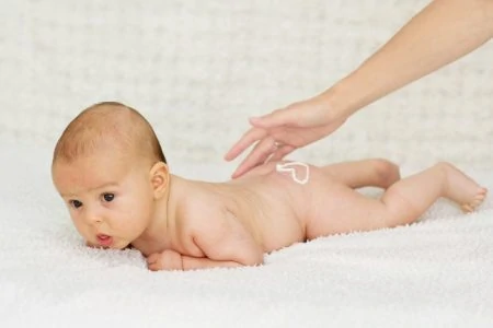 Mother rubbing baby lotion into her baby's skin