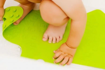 Baby crouching on a bath mat