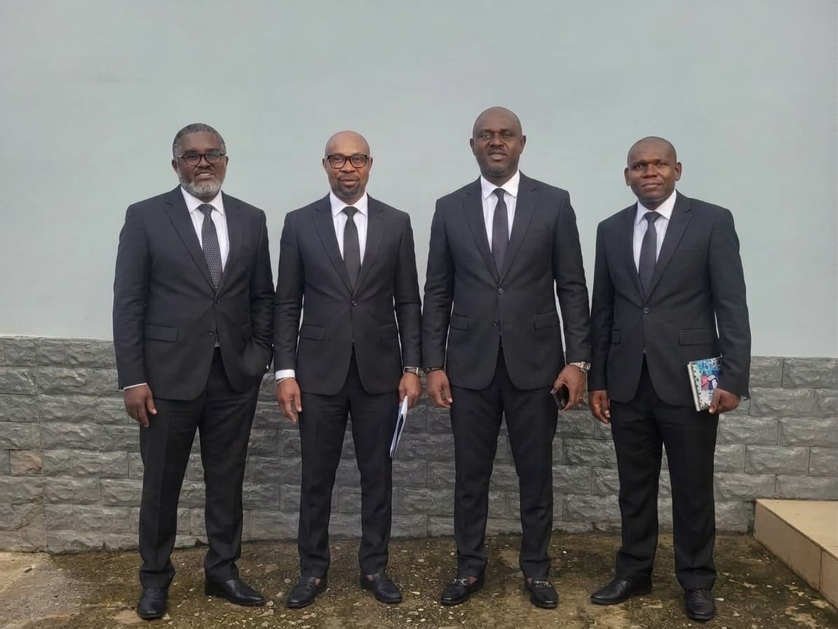 Four members of the protocol team in dark suits, standing together outside the church