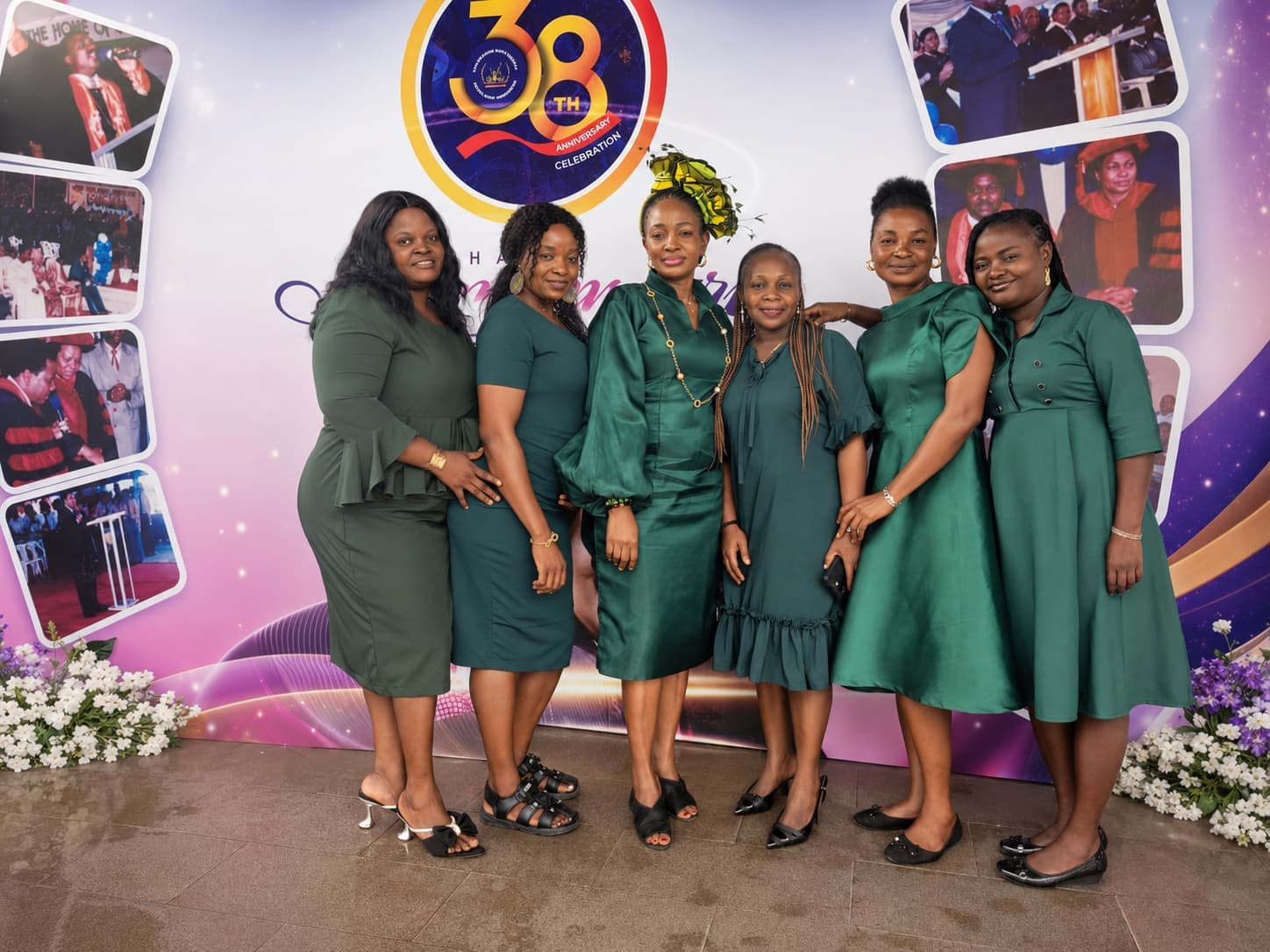 Six members of the ushering team in matching green, together in front of the church's anniversary backdrop