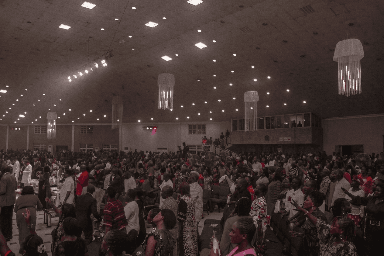 The Salem City of Faith congregation on their feet, hands raised in worship during a praise night service